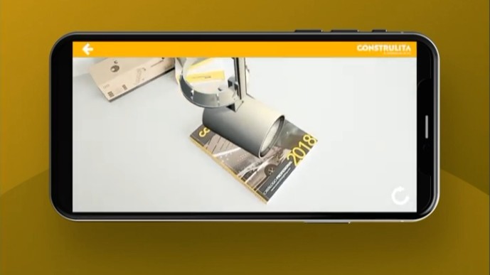 Phone screen showing a 3D luminaire in augmented reality on top of a printed 2018 catalog